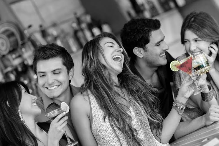 Happy group of friends at the bar having drinks