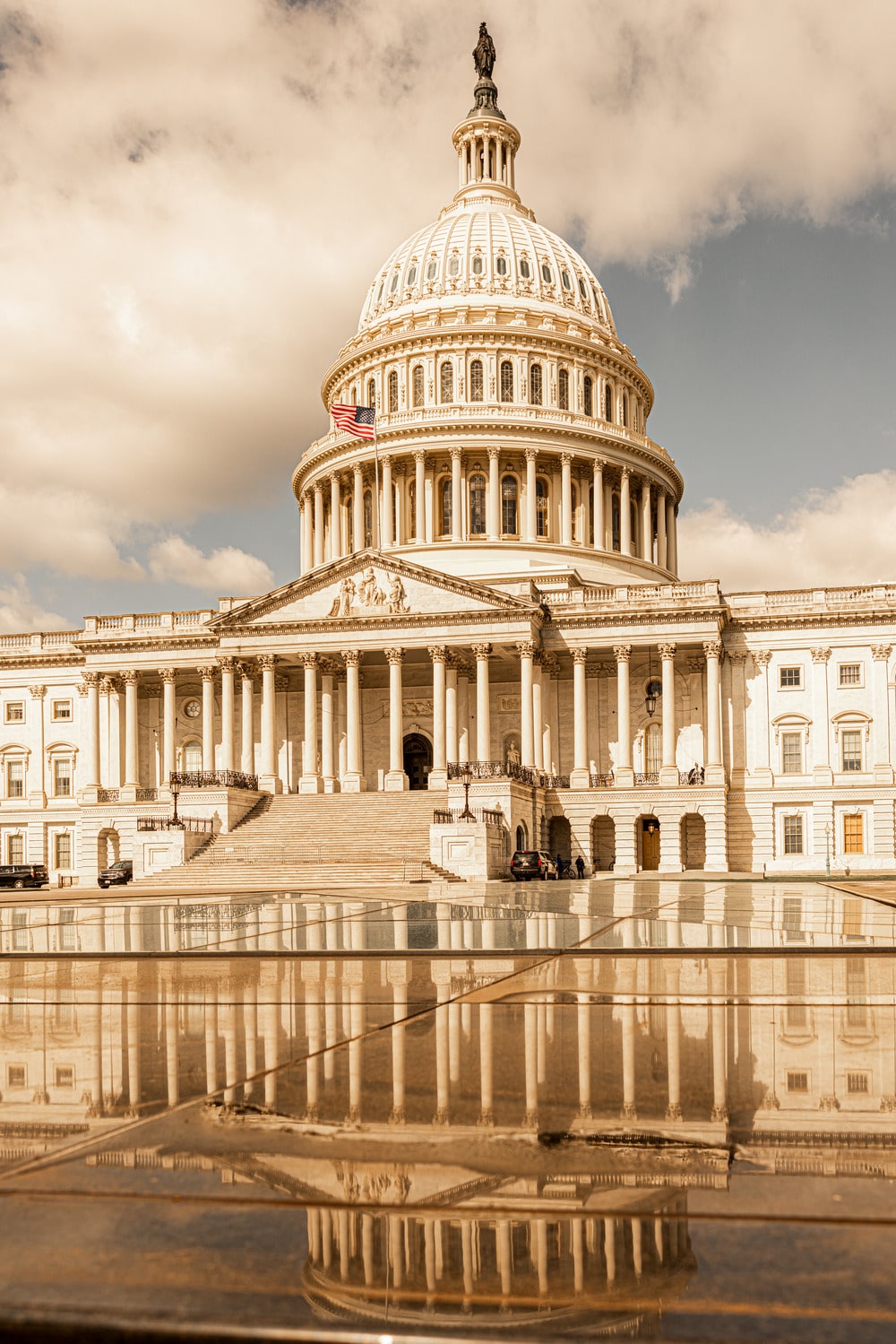 United States Capitol Building in Washington, D.C. with reflection on wet surface under cloudy sky