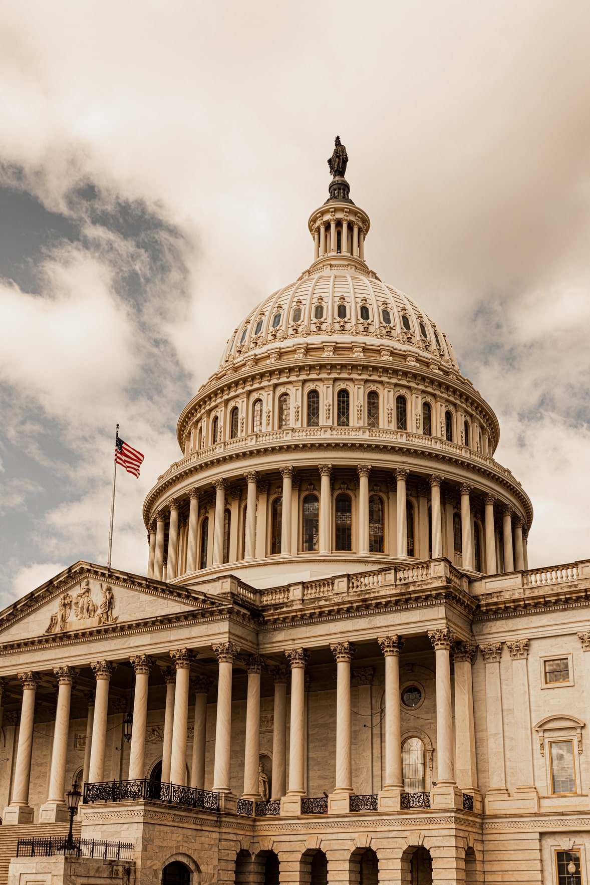United States Capitol Building with American flag on a cloudy day