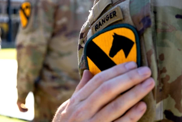 Soldier wearing the 1st Cavalry Division shoulder patch with a Ranger tab on a camouflage uniform