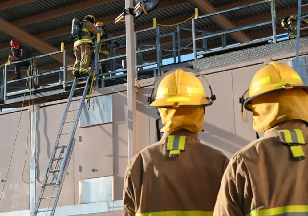 Firefighters in full gear participating in a training exercise with ladders at Goodfellow Air Force Base in Texas