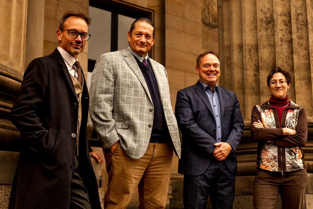 Four military lawyers from the Law Office of Will M. Helixon are standing in front of a building