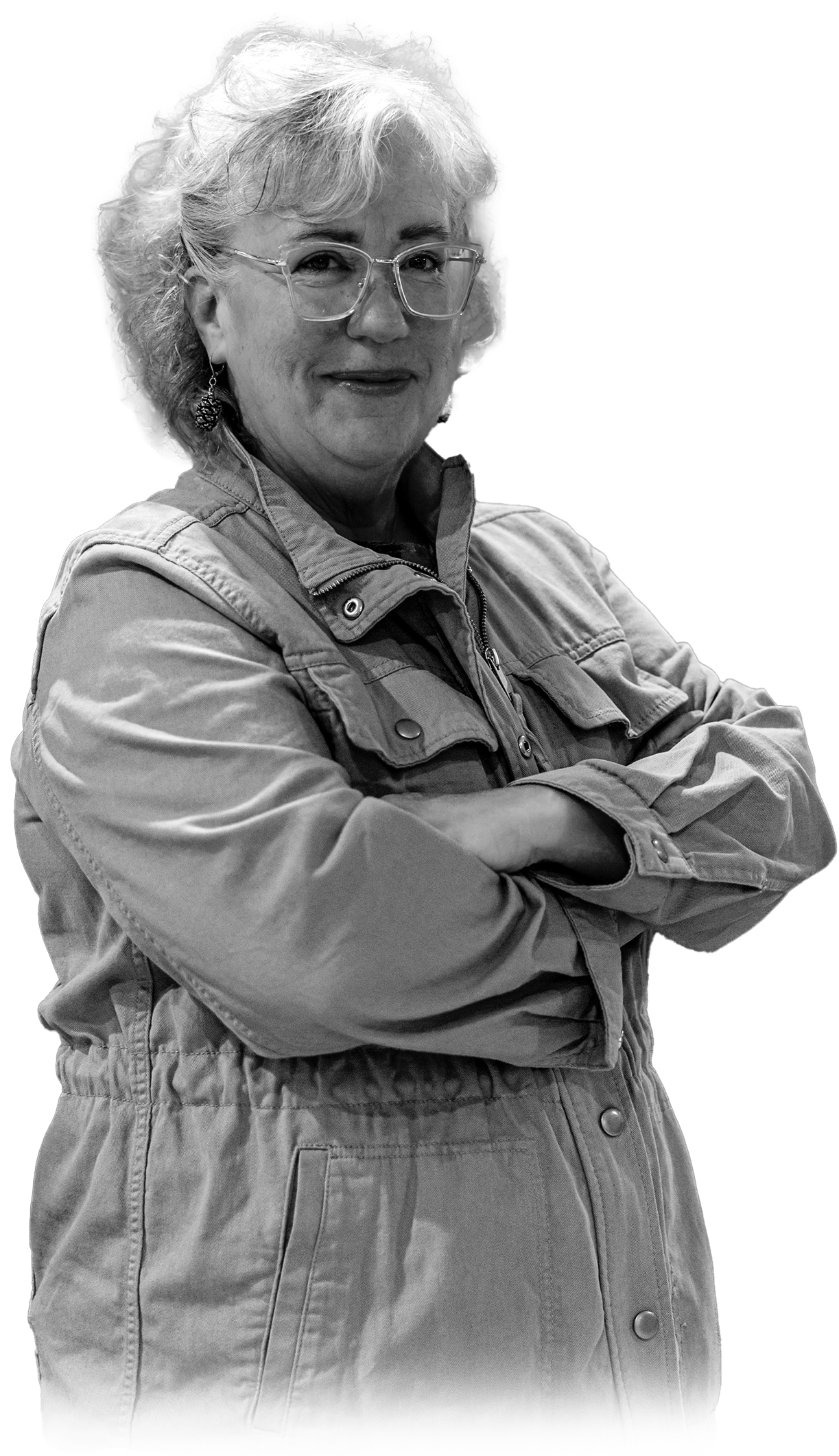 Genie Hughes standing with arms crossed wearing glasses and jacket in black and white portrait