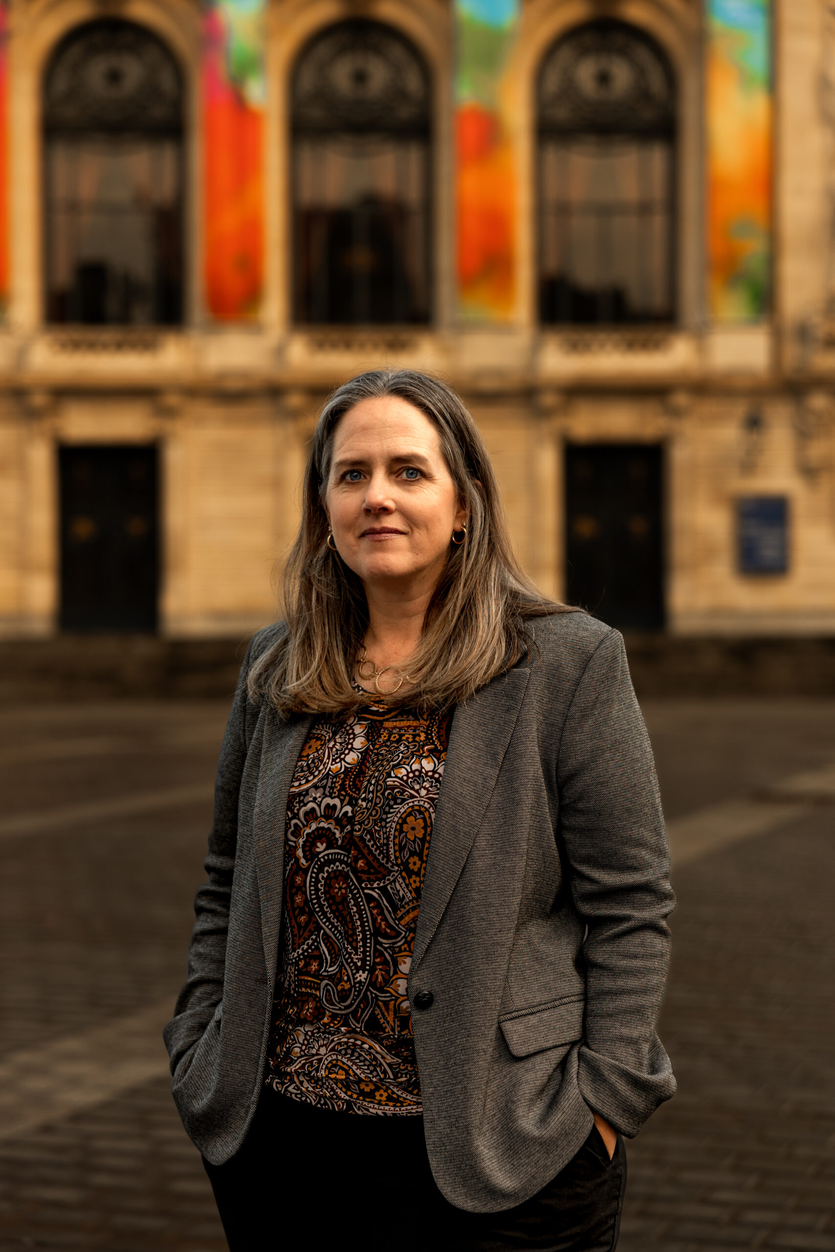 Kyle Meisner posing in front of historic European-style buildings, wearing a gray blazer