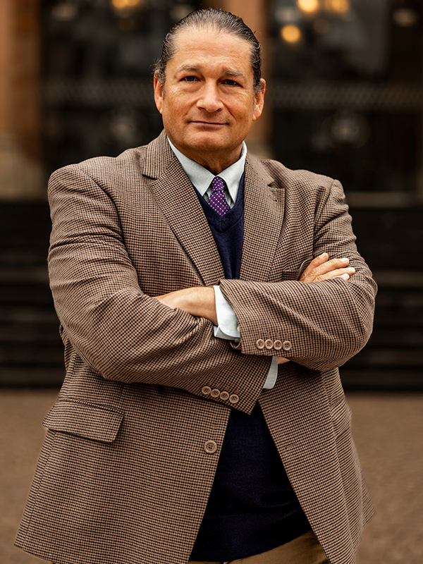 Will M. Helixon Military attorney Will M. Helixon standing with arms crossed in brown checkered suit jacket