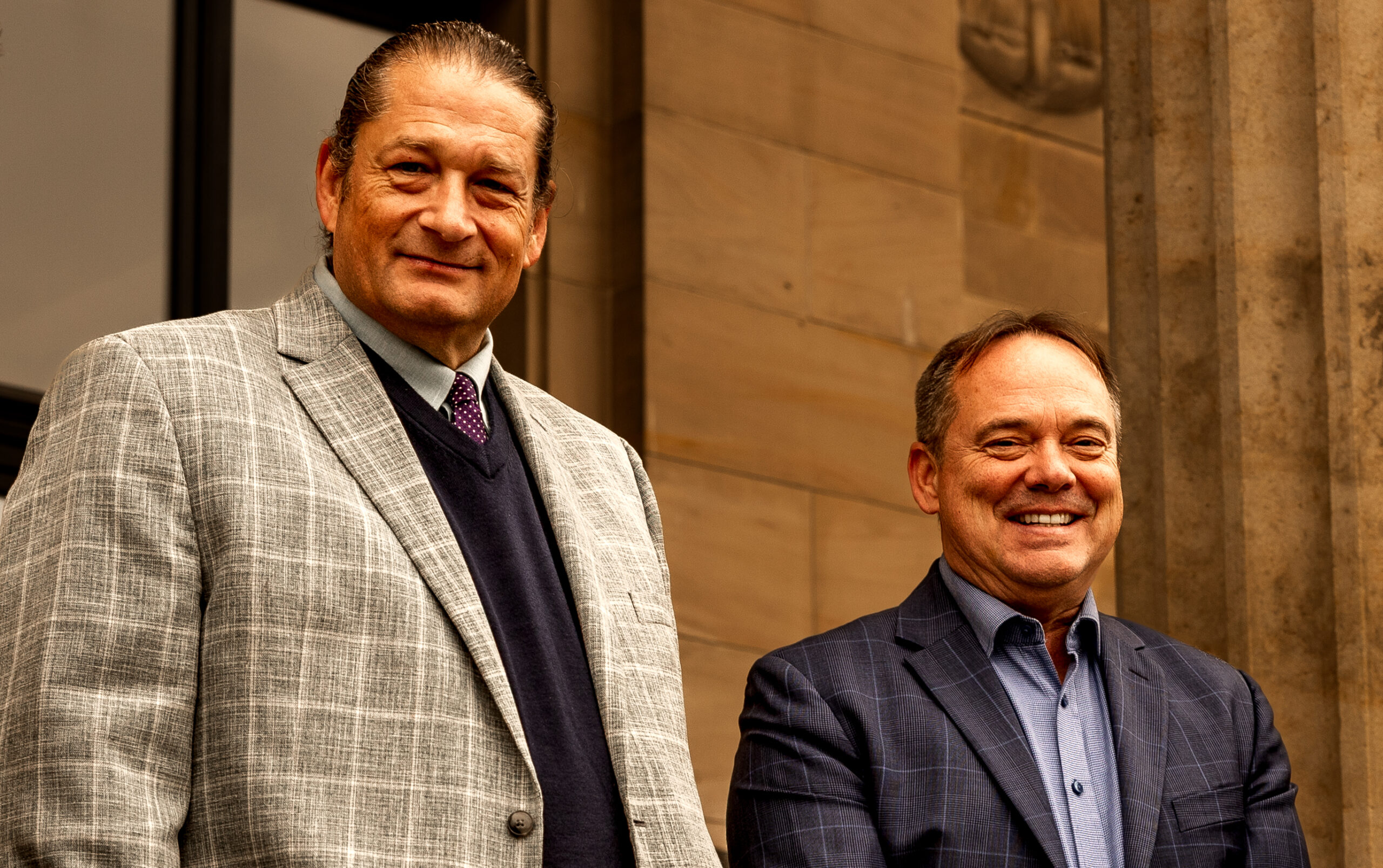 Scott Brokaw and Will M. Helixon standing together in business attire outside a building