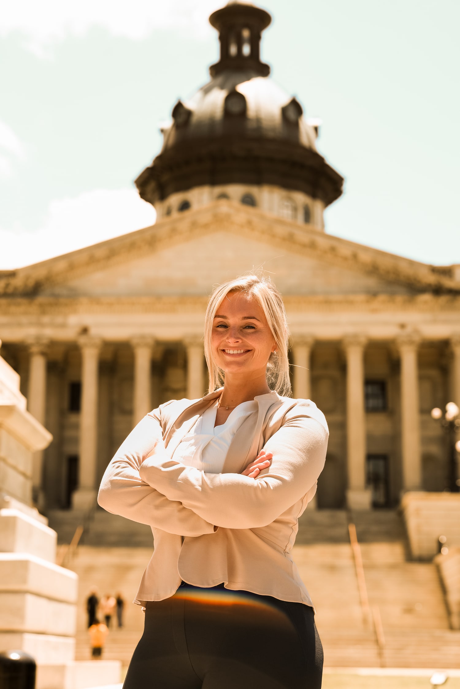 Stefany Garrick standing with arms crossed in front of a historic government building