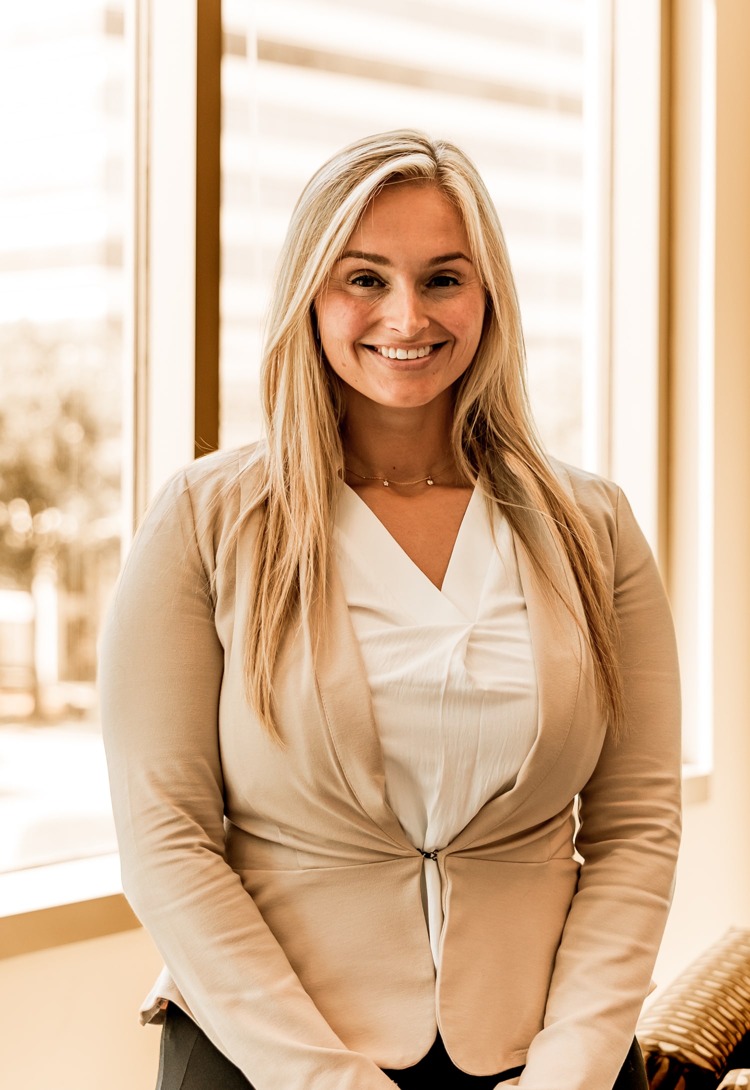 Stefany Garrick smiling indoors in business attire, standing by a window