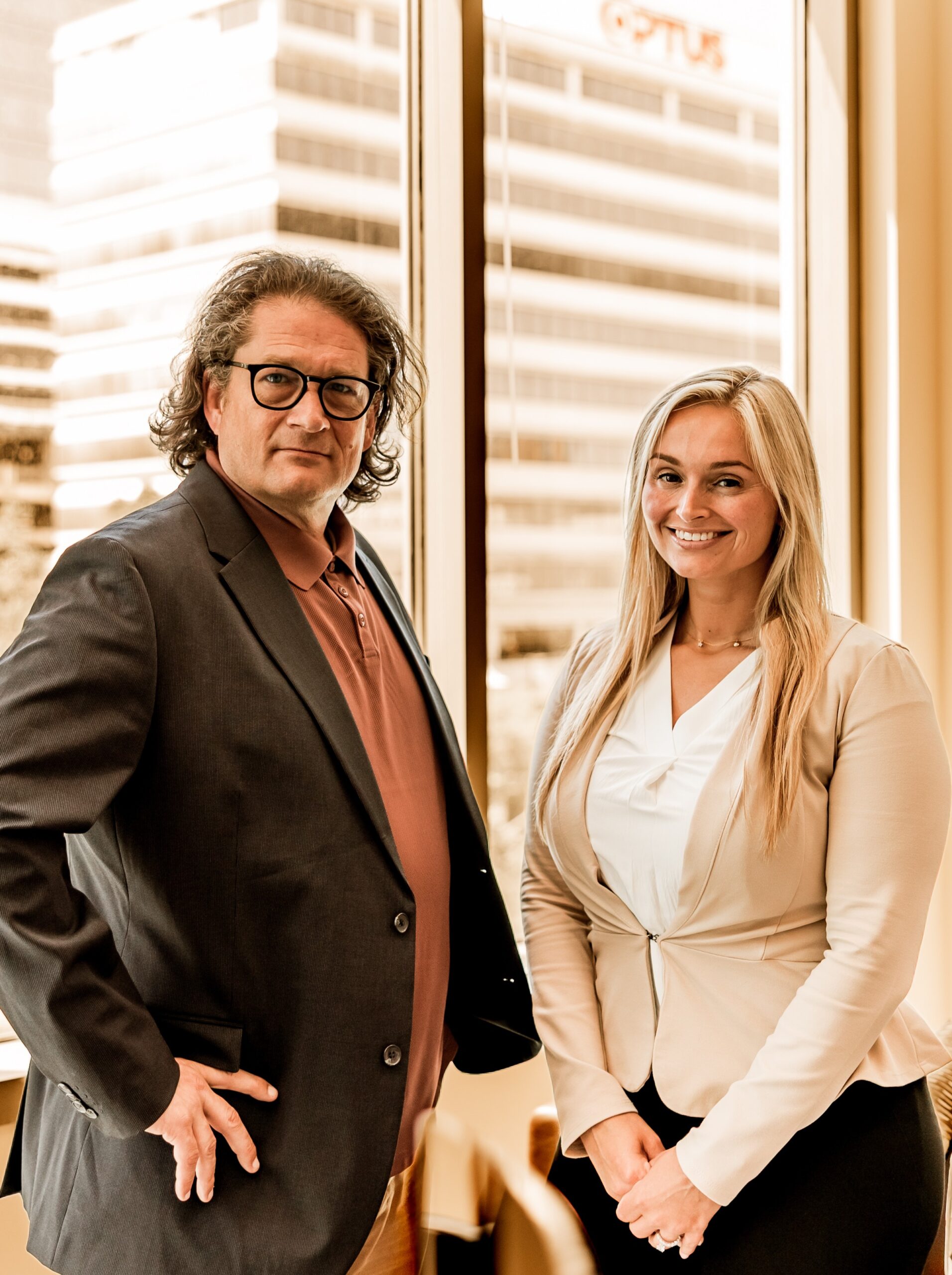 Stefany Garrick standing by an office window with Will M. Helixon