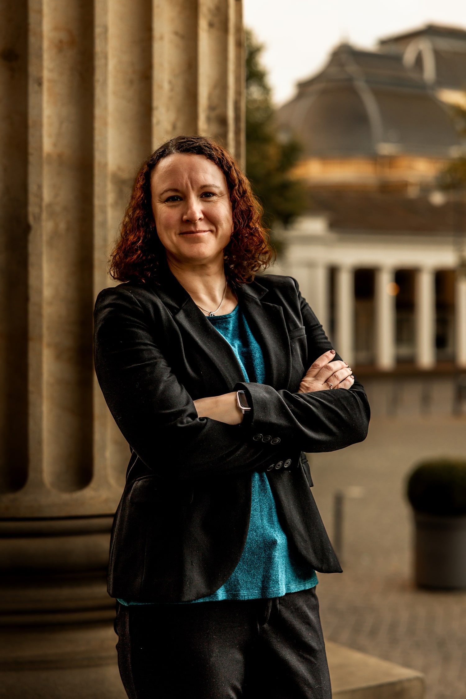 Victoria Camire leaning near a stone column outdoors, smiling confidently