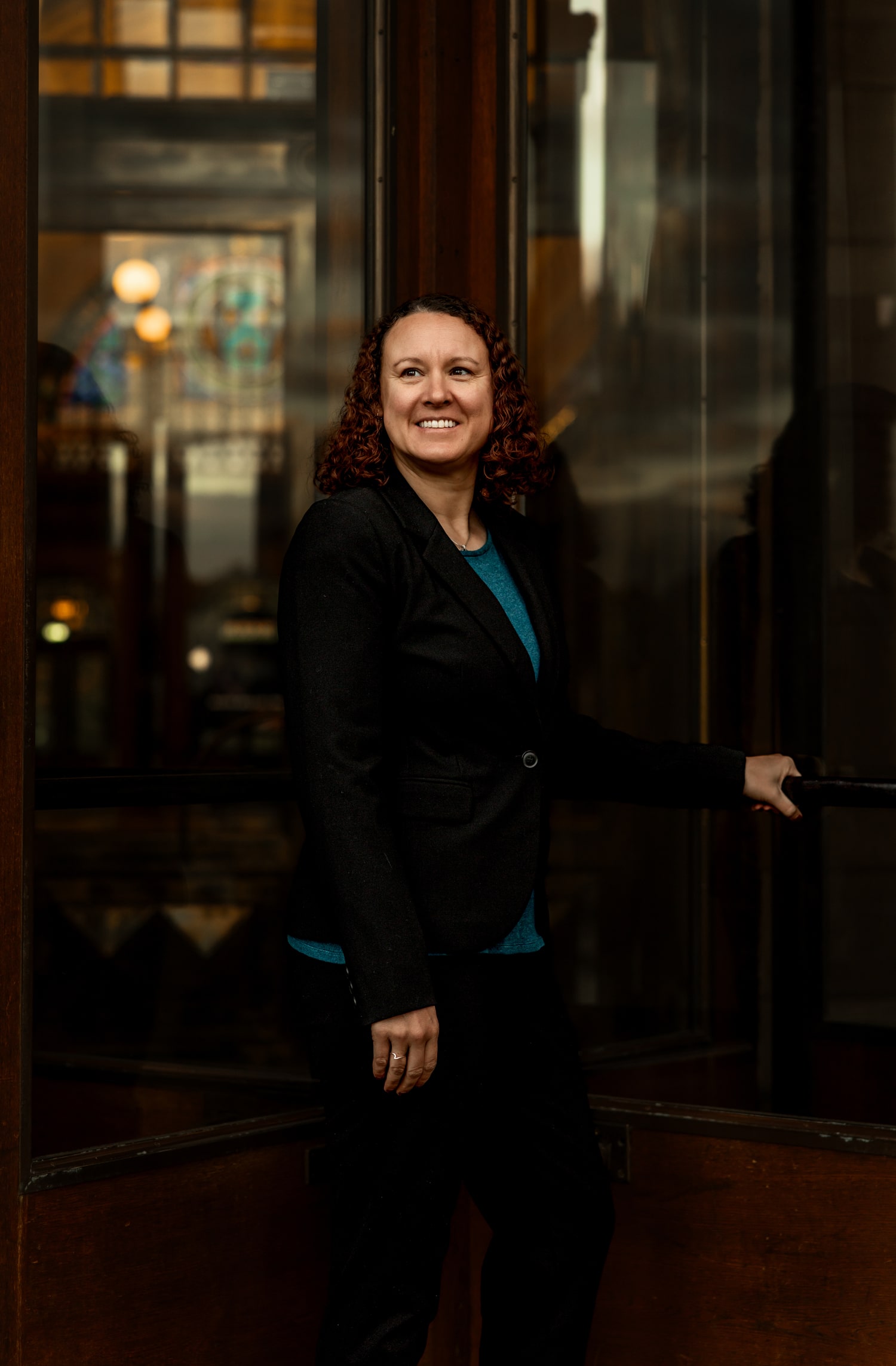 Victoria Camire smiling while holding a door open, framed by glass panels