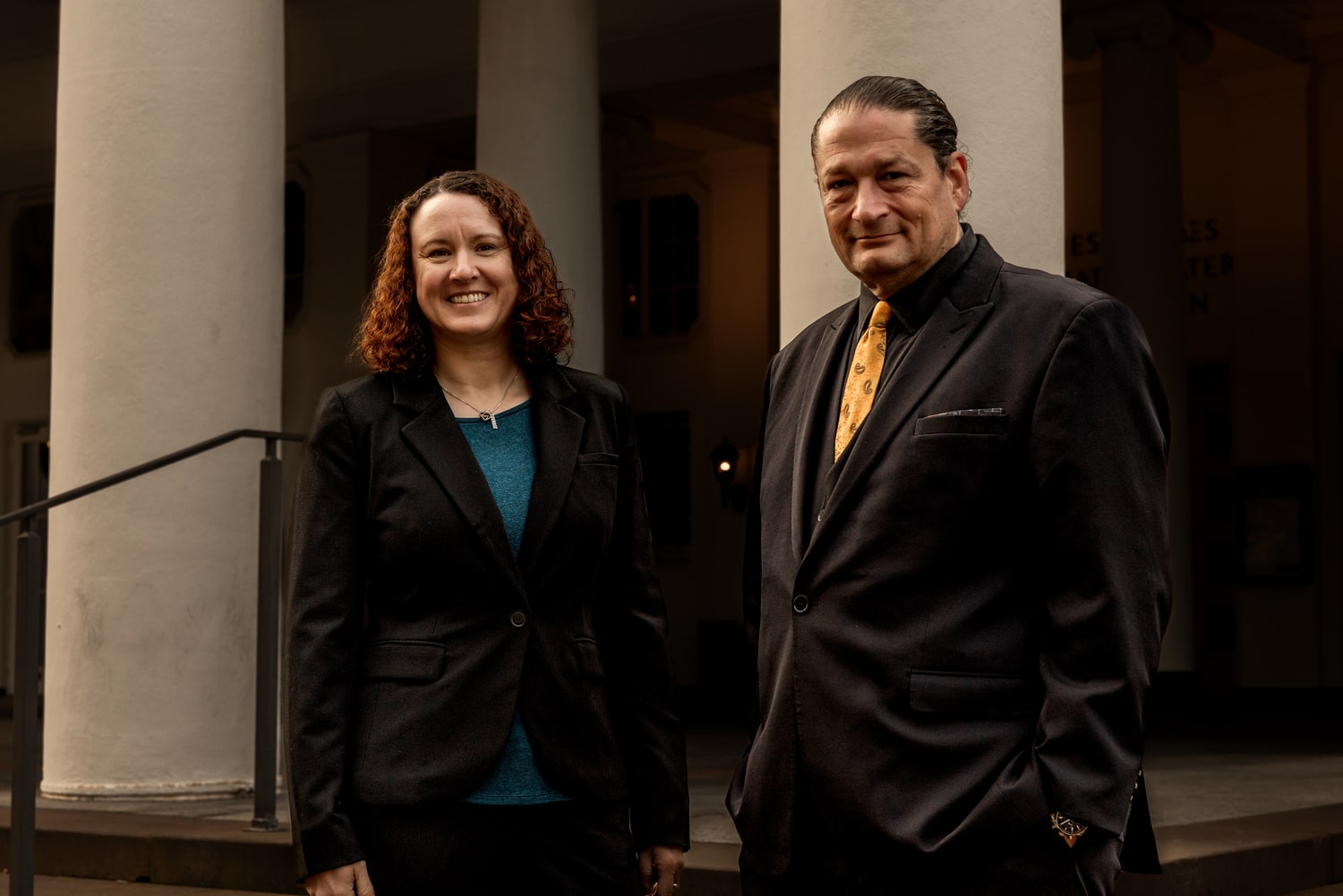 Victoria Camire and Will M. Helixon standing side by side outdoors in business attire