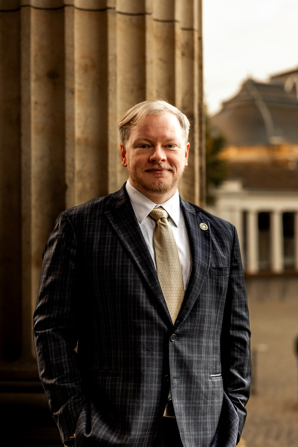 Military lawyer Cadman R. Kiker in dark checkered suitstanding by stone columns