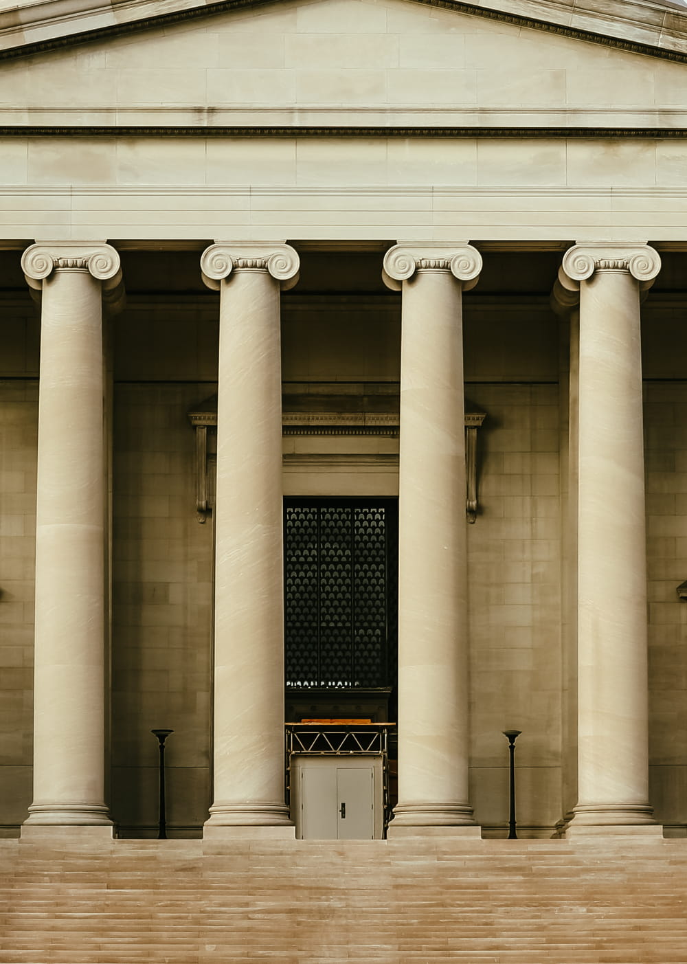 Neoclassical building facade with tall stone columns, front steps, and a central doorway
