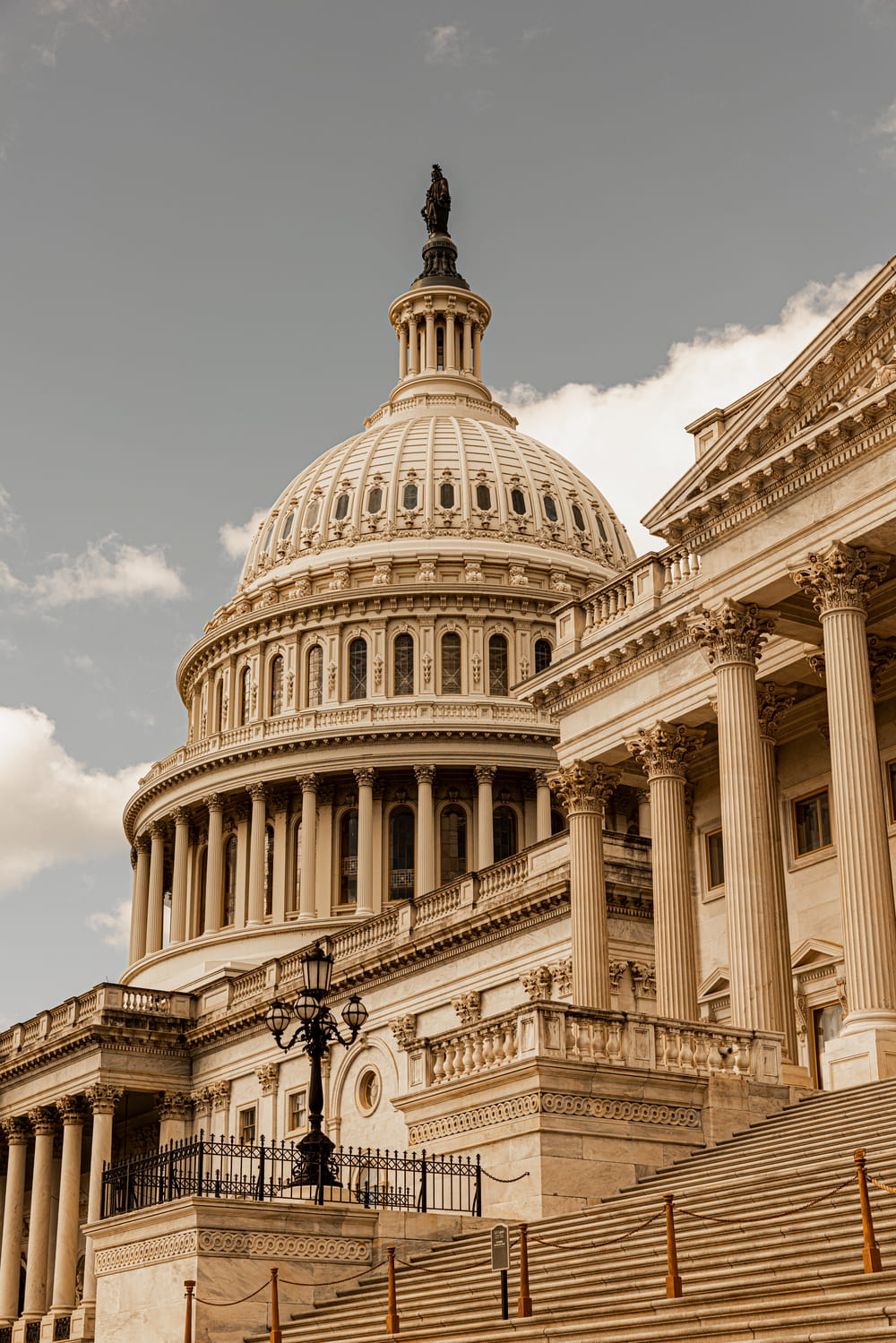 U.S. Capitol dome and classical columns viewed from a low angle under a cloudy sky