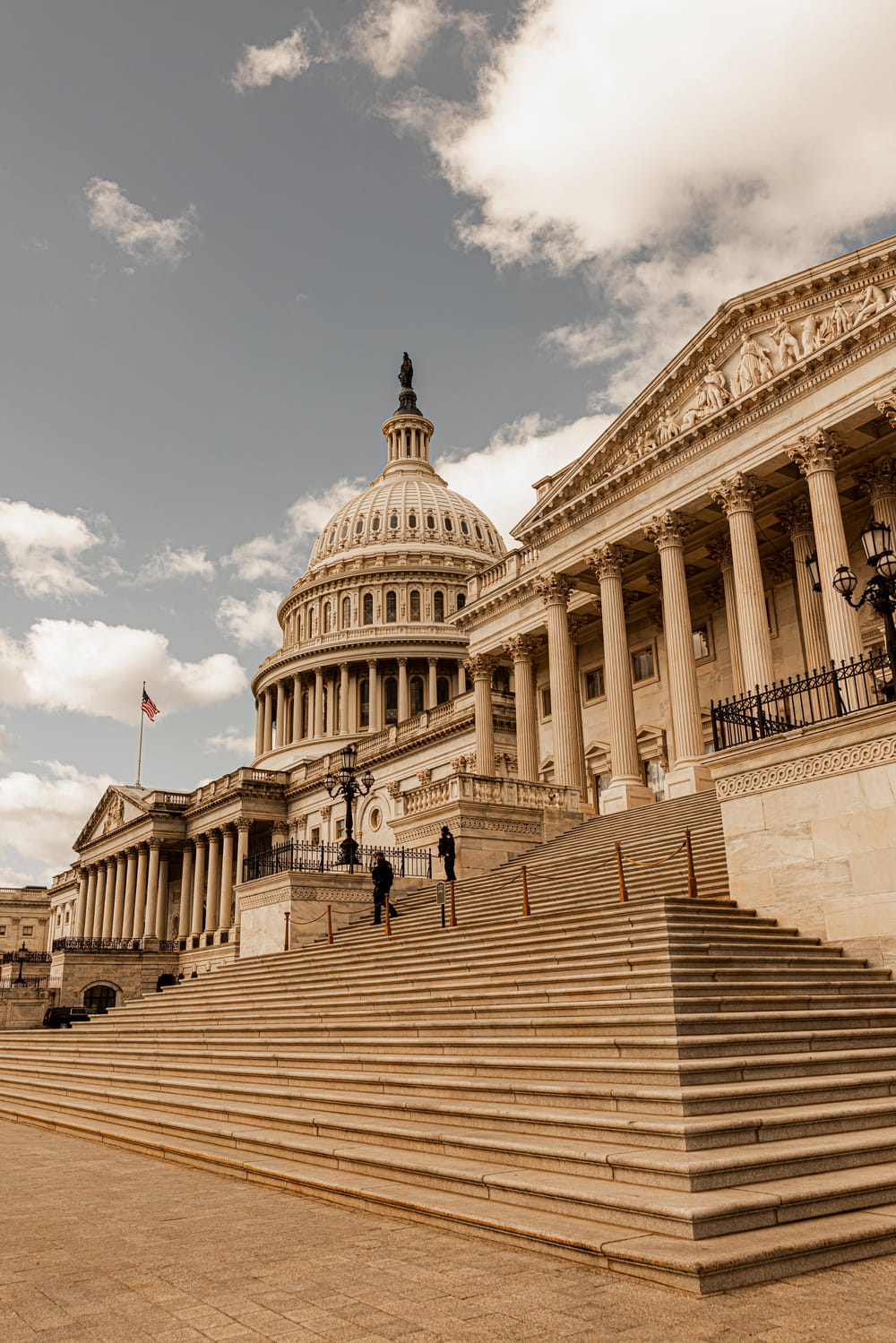 Wide view of the U.S. Capitol building with grand stone steps and cloudy sky