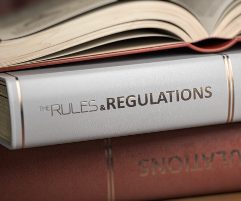 Book spine titled 'The Rules & Regulations' in a stack of law books