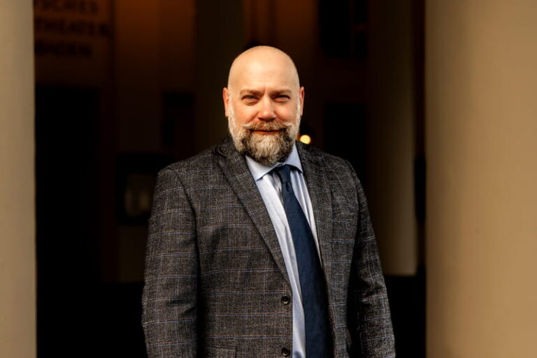 Matthew Krause, military defense attorney in a gray plaid tweed suit and navy tie
