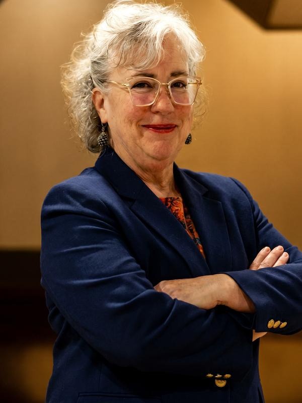 Genie Hughes, military lawyer, smiling in navy blazer with arms crossed