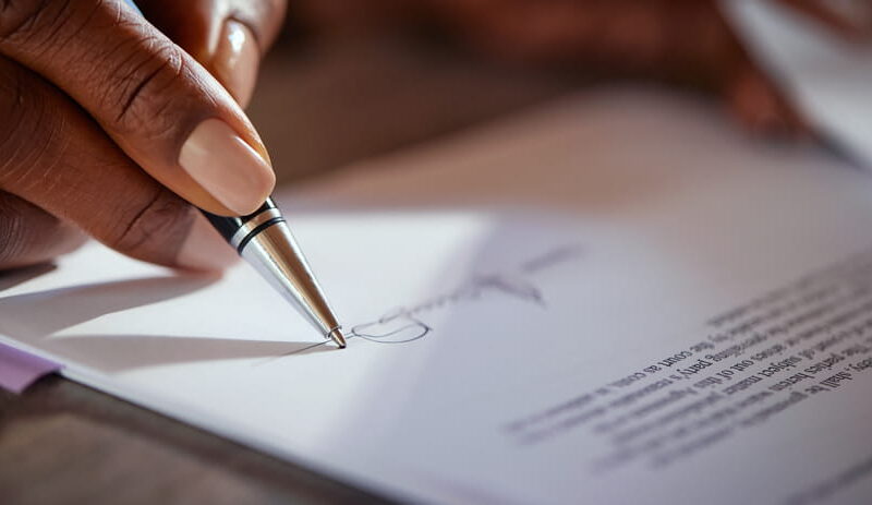 Close-up of a hand signing a legal document in ballpoint pen