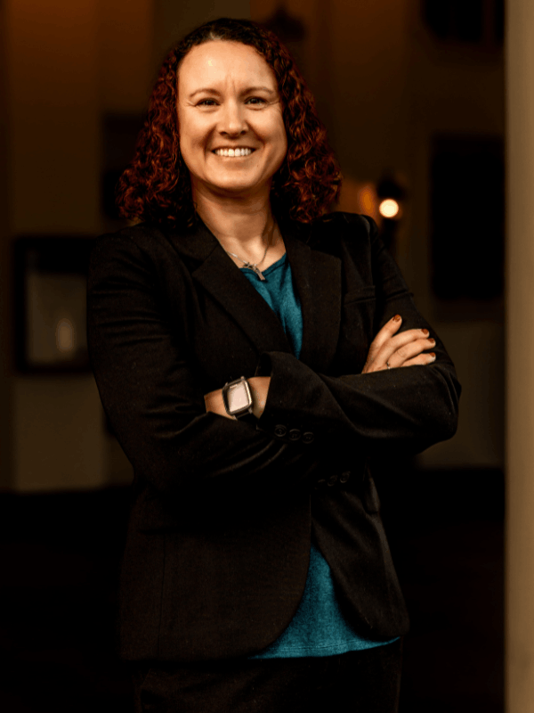 Victoria Camire, military defense attorney, smiling in a black blazer with arms crossed