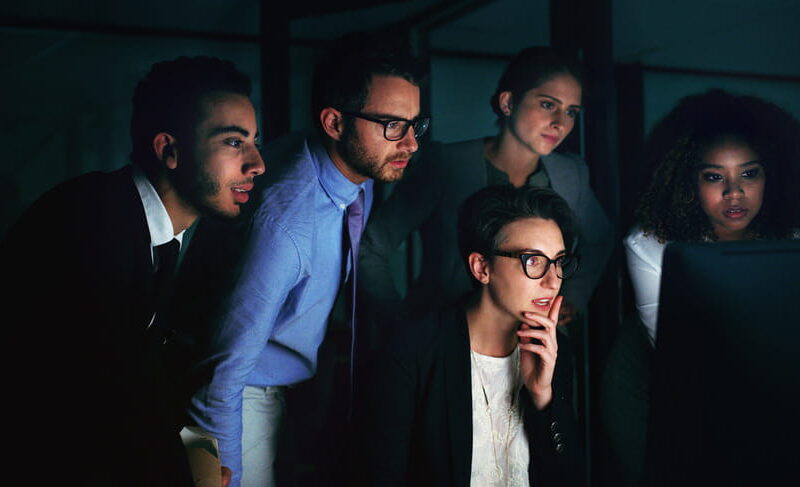 Group of federal employees reviewing case information on a computer screen late at night