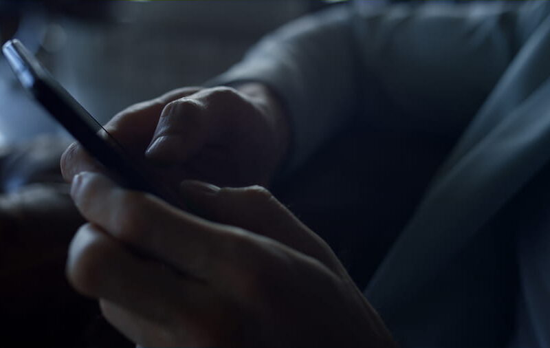 Close-up of hands holding a smartphone in dim light