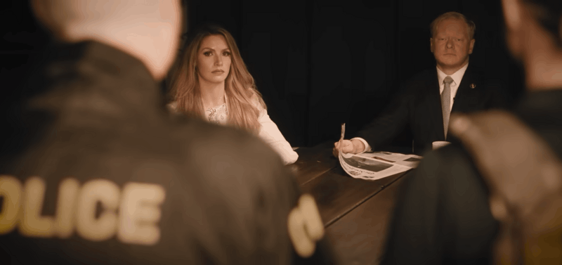 Military defense attorneys Laura Kiker and Cadman Kiker seated at a table as CID agents enter their home to conduct a search