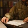 Service member in uniform reviewing documents at a desk