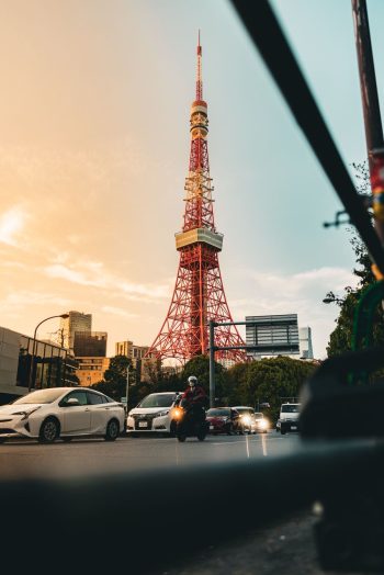 Tokyo Tower lit at sunset above evening traffic on a central Tokyo street