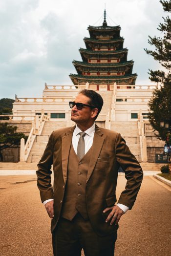 Will M. Helixon, South Korea military defense lawyer, hand on hip before the pagoda tower of the National Folk Museum of Korea